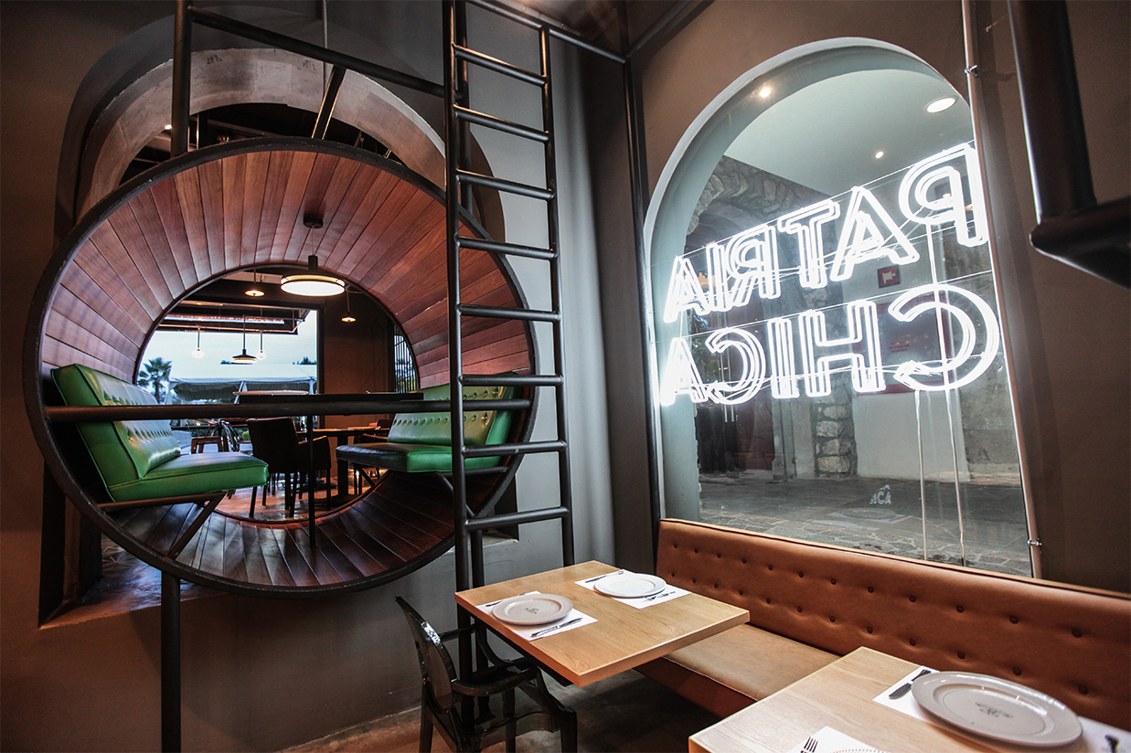 Acceso principal de restaurante Patria Chica con arco de ladrillo y vegetación, construcción de interiores Fer Et Ciment León